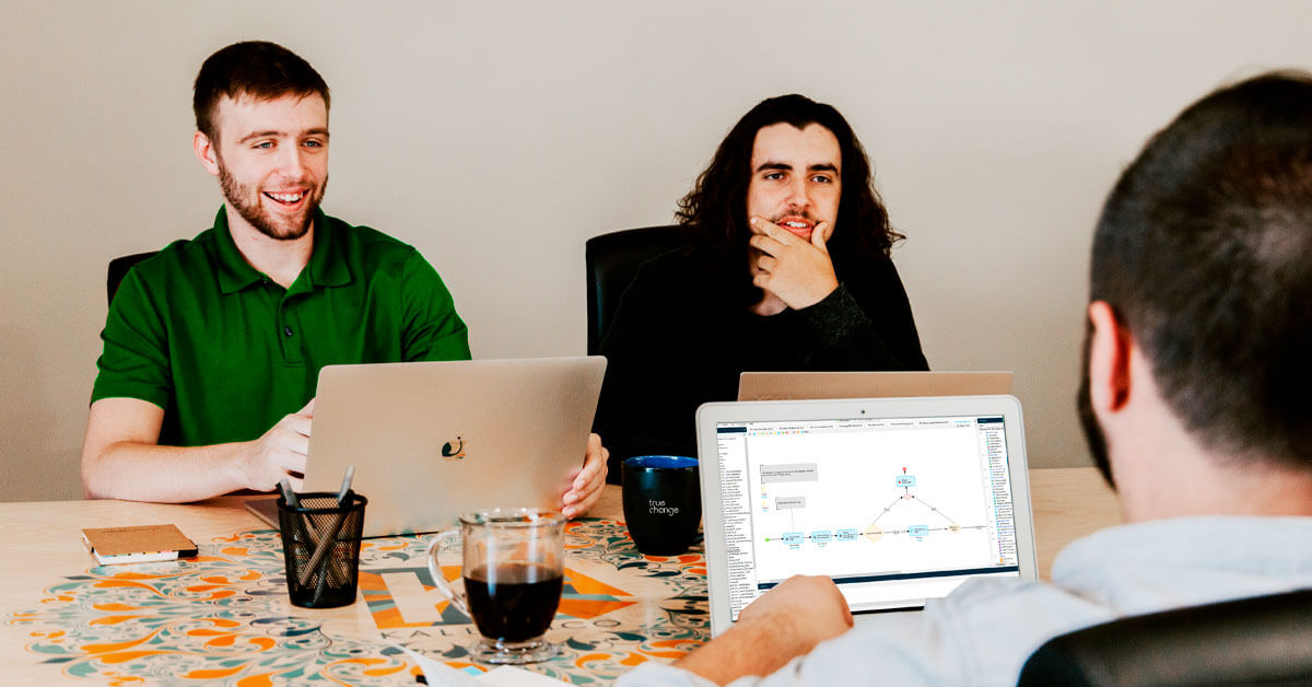 desenvolvedores sentados na mesa com notebooks discutem a viabilidade de plataformas low-code
